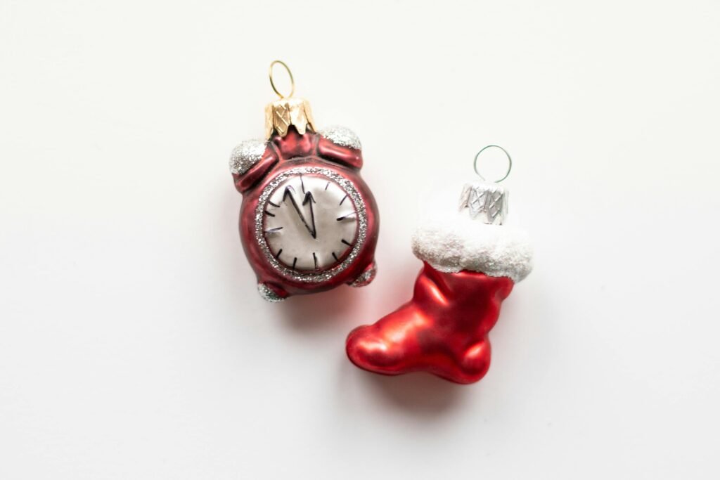 Close-up of red Christmas ornaments, including a clock and stocking, on a white background.