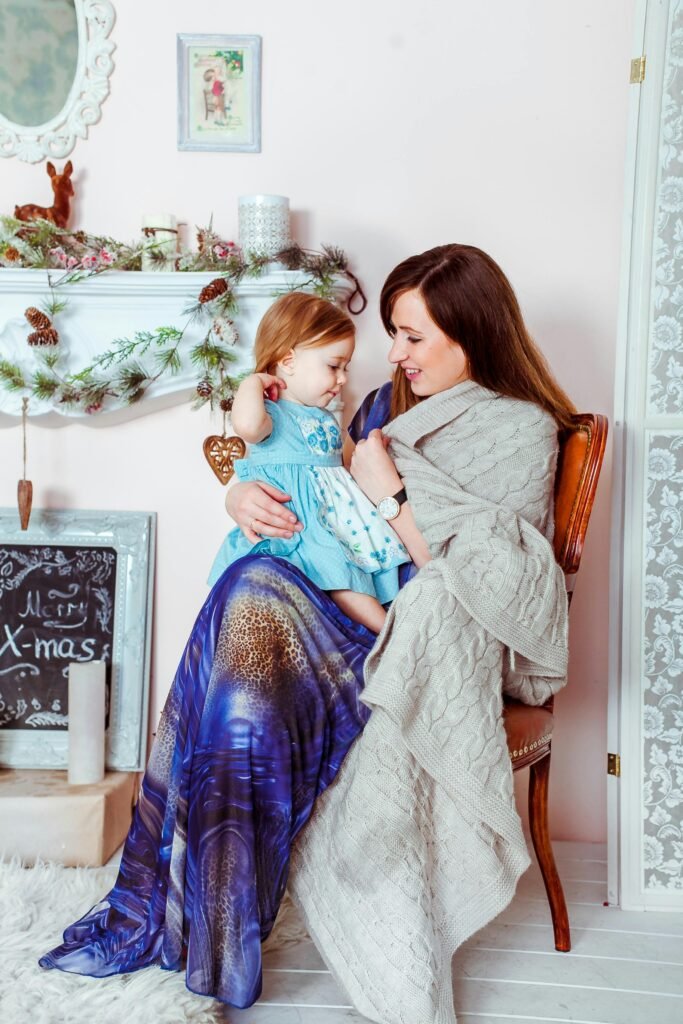 A mother lovingly holding her daughter, surrounded by cozy holiday decorations.