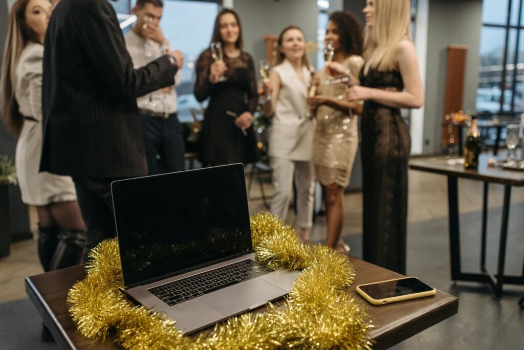 Colleagues celebrating at a festive office party with a laptop and decorations.